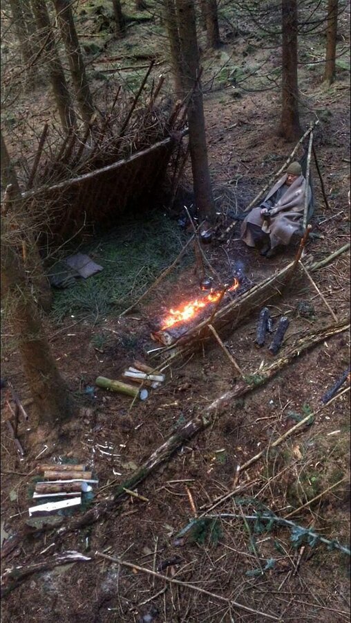 Lean-to shelter with bough bed, a tripod chair, and a long fire #survivalshelter.jpg