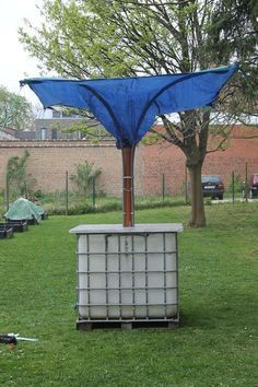 a blue umbrella sitting on top of a white box in the middle of a field.jpg